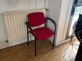 a red chair sitting in front of a radiator in a room