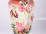 un vase avec des fleurs peintes dessus, posé sur une table