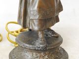 a bronze statue of a woman holding an umbrella