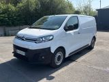 la camionnette blanche est garée sur un parking avec des arbres en arrière-plan