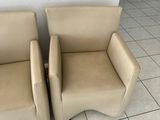 pair of tan leather lounge chairs on tile flooring in a room