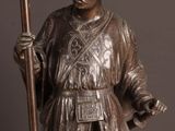 bronze statue of a man holding a torch in his right hand