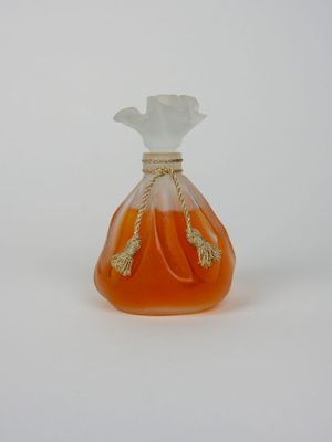 un flacon de parfum orange muni d'un bouchon blanc, posé sur une surface blanche