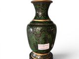 a green vase sitting on a stand on a white surface