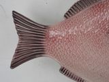 a pink fish that is sitting on a white surface