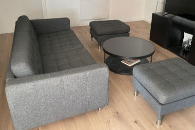 un salon avec un canapé, un fauteuil, une table basse et une télévision