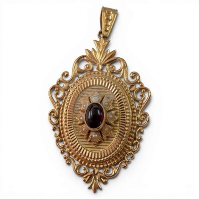 an image of a gold pendant with a garnet stone in the center
