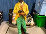 a statue of a man in a yellow jacket and hat on a table