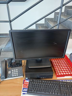 un bureau sur lequel se trouvent un ordinateur, un clavier, un téléphone et d'autres objets