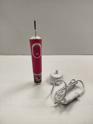 une brosse à dents rose posée sur une table à côté d'un chargeur