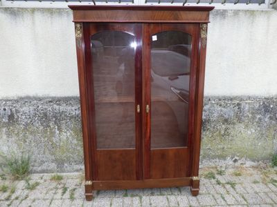 une armoire en bois avec des portes vitrées, placée contre le mur d'un immeuble
