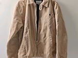 une veste beige suspendue à un mur à l'aide d'un cintre