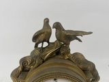 two birds sitting on top of a clock on a table