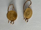 une paire de boucles d'oreilles dorées auxquelles est suspendue une pièce de monnaie