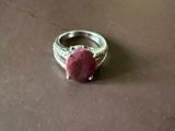 bague en argent ornée d'une pierre rose sur un fond marron