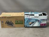 deux cartons de vêtements et un fer à repasser posés sur une table