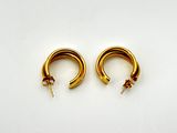 two gold hoop earrings on a white surface