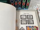 a book with stamps on it sitting on a table next to a stack of books