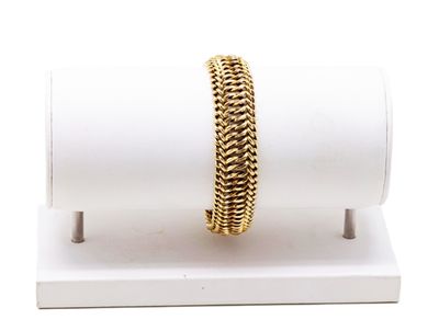 un gros plan d'un bracelet posé sur un présentoir, sur une surface blanche