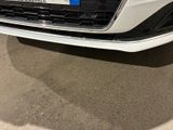 the front bumper of a white car with a number plate on it