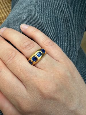 la main d'une femme tenant une bague sertie d'une pierre bleue