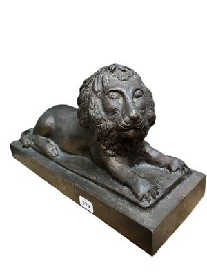 statue en bronze représentant un lion, posée sur un socle en pierre