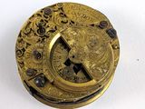 une assiette en or ornée d'une horloge, posée sur un fond blanc