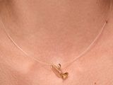 a close up of a woman wearing a gold necklace with two small gold hearts on it