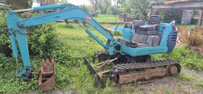 une petite pelleteuse bleue qui est garée dans l'herbe