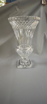 un vase en verre posé sur une table, avec un tissu en arrière-plan