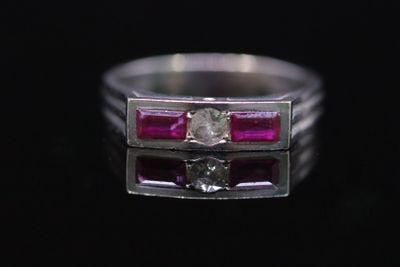 un gros plan d'une bague sertie d'un diamant et d'un rubis sur une surface noire