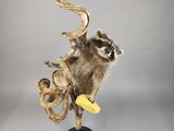 une sculpture représentant un raton laveur perché sur une branche, tenant une banane