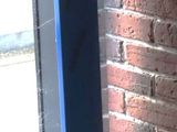 a blue speaker sitting on a window sill in front of a brick wall