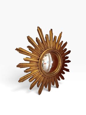 une image représentant un soleil rayonnant doré avec un miroir au centre
