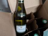 une bouteille de vin dans une boîte en carton, à côté d'une autre bouteille de vin