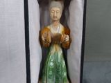 a figurine of a woman in a green dress in a box