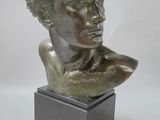 un buste en bronze représentant une femme, posé sur un socle noir