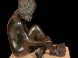 bronze sculpture of a woman sitting on a wooden base