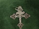 a silver cross with a bird on it on a green cloth