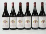 six bottles of red wine are lined up on a table