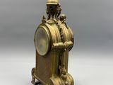 a gold clock sitting on a stand on a white surface