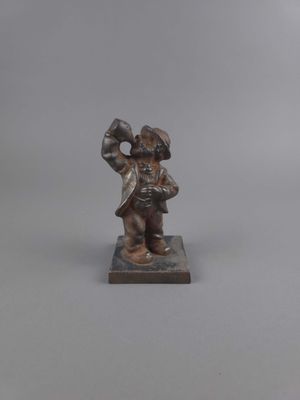 figurine représentant un homme portant un chapeau et un manteau, posée sur un socle