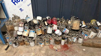 un tas de boîtes de conserve et de pots de peinture par terre
