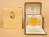une photo représentant un flacon de parfum dans un coffret, posé sur une table
