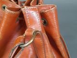 an orange purse sitting on top of a table next to a gray wall