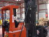 a forklift in a warehouse with pallets in the background
