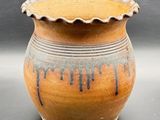 a brown vase with black drips on it sitting on a table