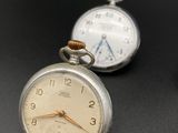 two old pocket watches sitting next to each other on a table