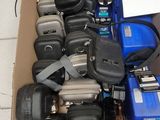 une boîte en carton remplie de téléphones portables de toutes sortes, posée sur un sol carrelé