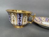 an image of a purple and gold cup and saucer on a table